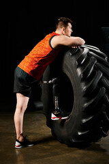 A man with a prosthetic leg stands next to a massive tire, ready to embark on a challenging workout...