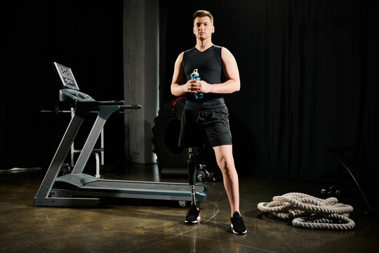 A man with a prosthetic leg stands in front of a treadmill, ready to work out in the gym. - Powered by Adobe