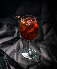 Glass of a cocktail with ice cubes on the dark background