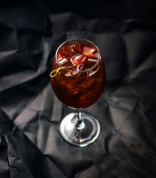 Glass of a cocktail with ice cubes on the dark background