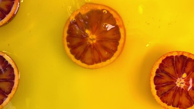 close up of natural red orange slices in juice, advertising of tropical fruit juice, background, slow motion