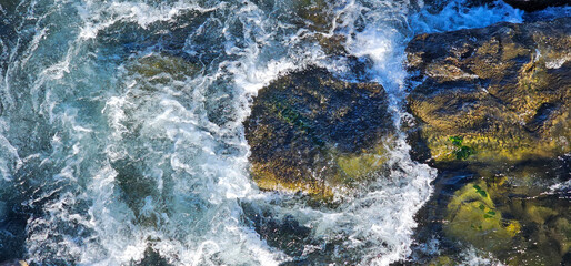 Aerial view of powerful waves crashing over rocks with seaweed; drone view of waves pounding...