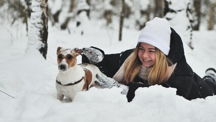 Fototapeta na wymiar A girl playing with her Jack Russell Terrier dog in the snow.