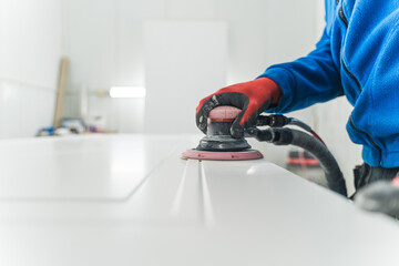 Professional carpenter using orbital power sander and then polishing surface with sand paper while...