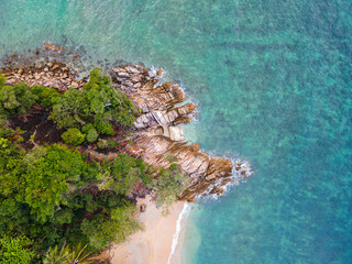 Aerial top down view of a beach with turquoise clear water rocks and trees in Koh Phangan Thailand