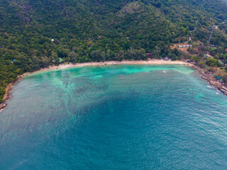 Aerial view of a beach with turquoise clear water and trees and hills in Koh Phangan Thailand