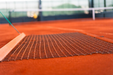 tennis player drag brushing the orange clay to maintenance clay court surface