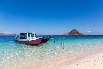 Boat at a beach in Indonesia with turquise blue water and white sand