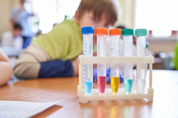 Colorful test tubes in a lab setting, with students, children in the background. Ideal for...