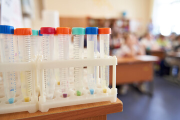 Vibrant lab test tubes in a rack, set against a blurred classroom backdrop. Perfect for educational...