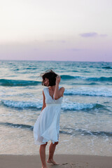Happy traveler girl in a white summer dress enjoying a tropical paradise beach with turquoise sea.