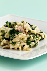 Homemade vegan spinach and portobello mushroom risotto on a white rectangular plate. Healthy eating concpt.
