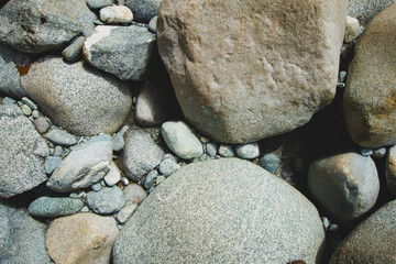 Closeup of scattered larger and smaller stones along coastside