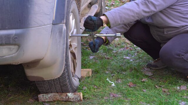 One man helps another to unscrewing car wheel nuts using a large pipe. Large lever.
