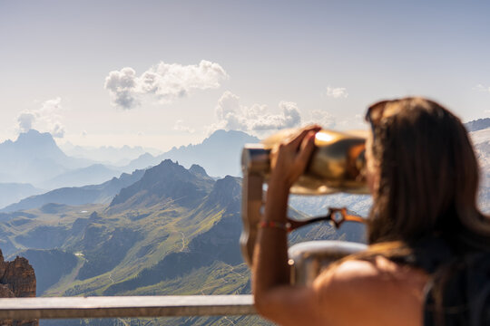 woman on top of the mountain using binoculars to contemplate the mountains