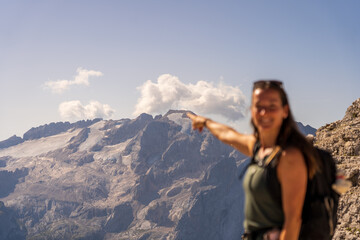 backpacker woman pointing to the top of mountains in Dolomites. Italy