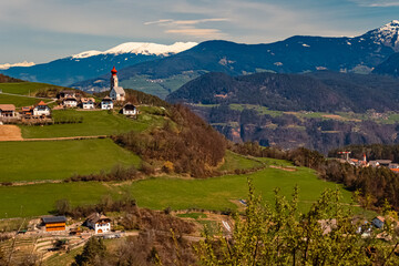 Alpine spring view with a distant church seen from near Klobenstein, Ritten, Eisacktal valley,...