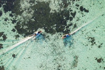 Two longtail boats meeting each other on the sea with the corals in the background