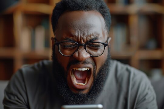 Close-up of an African American man shouting at his phone, showing visible frustration and anger