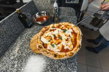 The pizza maker takes out the finished pizza from the electric oven. pizzaiolo holds a pizza. High quality photo