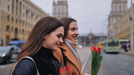 two beautiful young women walking together along a city street