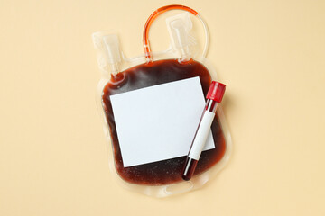 Bag and test tube with donor blood on beige background, top view