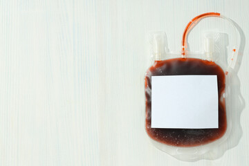 Bag with donor blood on white wooden background, space for text
