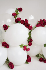 Garland of white balloons and burgundy roses.