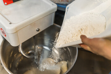 adding flour into the electric mixer machine to knead the dough, kitchen concept. High quality photo