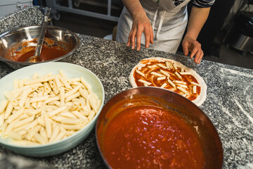 chef putting penne macaroni and tomato sauce on pizza, italian cuisine, . High quality photo