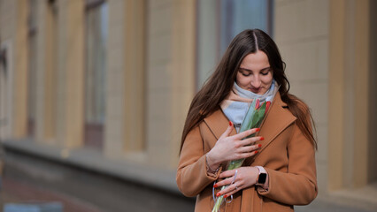 Portrait of a happy shade girl with a tulip in the background of the city in the cold season.