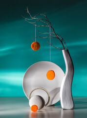 Modern still life with a dry branch in a white vase and a carrot