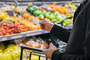 Male customer paying for groceries at supermarket using his credit card. Seamless checkout: Payment cards offer ease and convenience at the supermarket