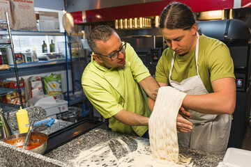 chef helping his student to make pizza dough at the bakery kitchen. High quality photo