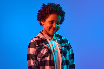 Portrait of smiling African-American girl in checkered shirt, short curly hair standing against...