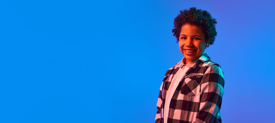 Portrait of smiling African-American teen girl in casual clothes, checkered shirt, posing against...