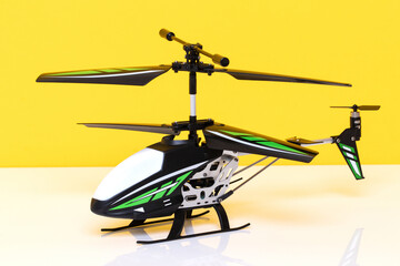 Closeup of a little remote controlled toy helicopter on a bright table against yellow background. Macro photograph of RC helicopter.