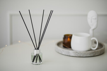 Still life with white mug, aromatic sticks and candles on a table in a cozy living room.