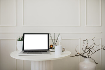 Laptop and white mug with tea on a table. Workspace in a modern room.