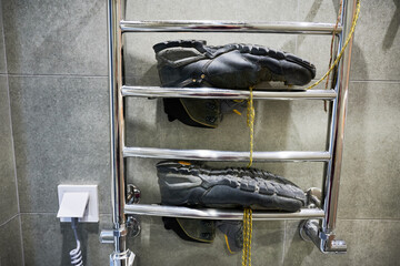 Hiking shoes drying after big camping. Black boots for hiking lying on dryer in bathroom.
