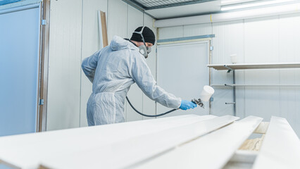 Man painting furniture details. Worker using spray gun. View of the paint shop of carpentry. High quality photo