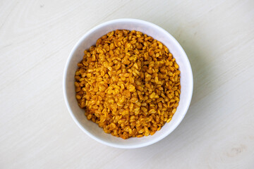 Moong dal namkeen on a white bowl on wooden background. It is considered one of the healthiest snacks in the world. Top view