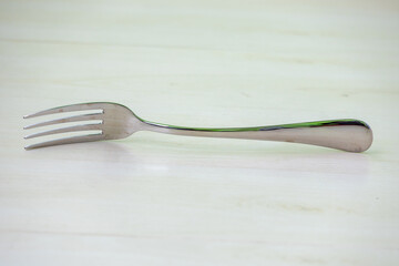 A steel fork spoon placed on a wooden textured background