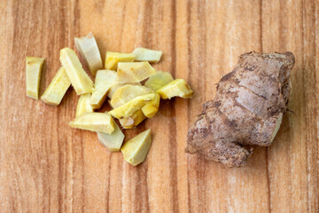 Sliced ginger pieces root and whole ginger on a wooden background.