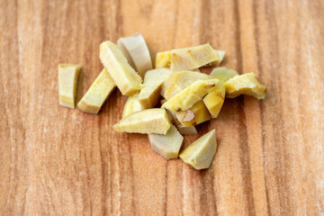 Freshly sliced ginger pieces on a wooden background.