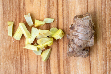 Fresh ginger pieces and whole ginger on a wooden background.