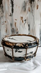 A black and white drum with gold accents sits on a white background.
