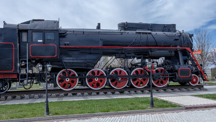 A steam locomotive with a steam power plant using steam engines as an engine. Mainline passenger steam locomotive. Ancient railway transport. Transportation of goods by rail.