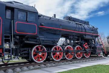 Fototapeta na wymiar A steam locomotive with a steam power plant using steam engines as an engine. Mainline passenger steam locomotive. Ancient railway transport. Transportation of goods by rail.