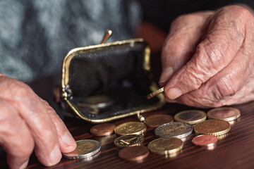 Detailed closeup photo of elderly 96 years old womans hands counting remaining coins from pension...